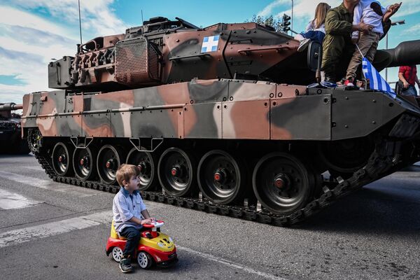 2023年10月28日希臘“說不”國慶紀念日，在塞薩洛尼基舉行閱兵式上，一男孩開著玩具車經過“豹 2A6 HEL”主戰坦克。 - 俄羅斯衛星通訊社