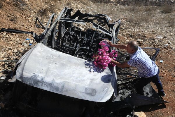 一名黎巴嫩男子在汽车残骸前献花，他的亲属在以色列对黎巴嫩南部靠近以色列边境的袭击中丧生。 - 俄罗斯卫星通讯社