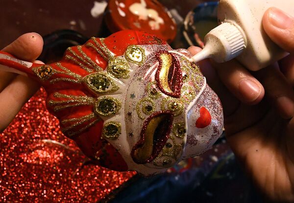在克拉斯诺亚尔斯克的“比留辛卡”玩具厂，一名艺术家在用传统技术制作的“金面具”戏剧奖形式的玻璃新年装饰上进行手绘。 - 俄罗斯卫星通讯社