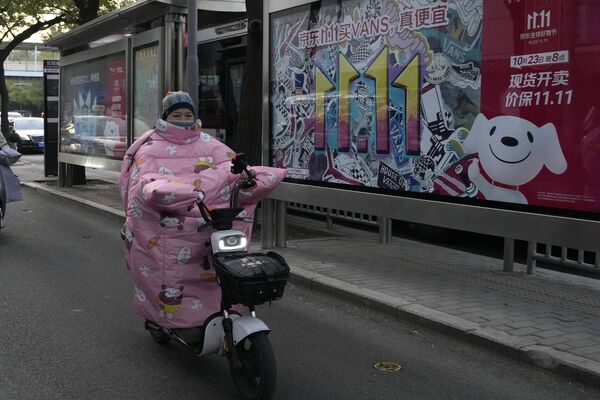 一名女士騎車經過北京的雙十一廣告。 - 俄羅斯衛星通訊社