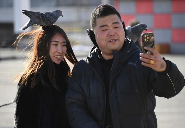 遊客在符拉迪沃斯托克中央廣場與鴿子合影。 - 俄羅斯衛星通訊社
