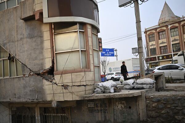 12月19日，甘肃省积石山县大河家，一名男子在地震后的街道上行走。 - 俄罗斯卫星通讯社