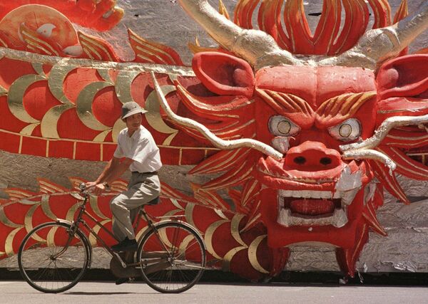 1997年7月4日，北京工体外，一名中国男子骑车经过庆祝香港回归演出中使用的龙头花车。 - 俄罗斯卫星通讯社