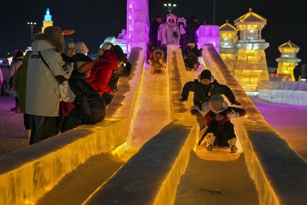 2024年1月8日，游客们在哈尔滨冰雪大世界的冰滑梯游玩。(Wayne Zhang/美联社） - 俄罗斯卫星通讯社