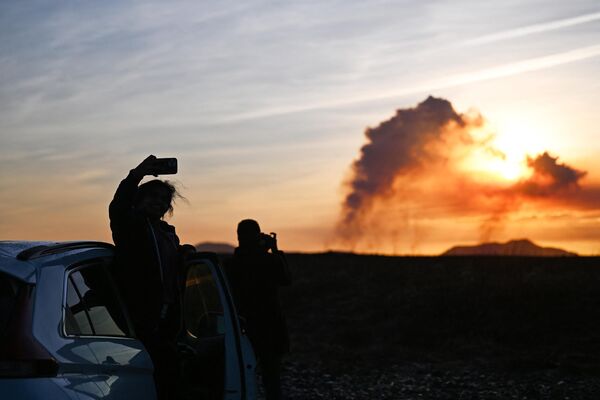 2024年1月14日，在冰島凱夫拉維克附近，人們站在他們的汽車旁邊拍照，因為火山噴發時煙霧滾滾。據冰島公共廣播電台RUV報道，夜間地震活動加劇，格林達維克的居民被疏散。這是冰島兩年來的第五次火山噴發，上一次是在2023年12月18日，在首都雷克雅未克西南的同一地區。冰島有33個活火山系統，是歐洲最多的。 - 俄羅斯衛星通訊社