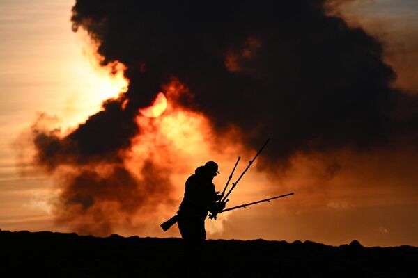 2024年1月14日，在冰岛的凯夫拉维克附近，一名男子在调整他的摄影设备，因为在格林达维克附近的火山喷发期间，烟雾滚滚。据冰岛公共广播电台RUV报道，夜间地震活动加剧，格林达维克的居民被疏散。这是冰岛两年来的第五次火山喷发，上一次是在2023年12月18日，在首都雷克雅未克西南的同一地区。冰岛有33个活火山系统，是欧洲最多的。 - 俄罗斯卫星通讯社