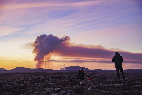 2024年1月14日星期日，冰岛格林达维克附近，人们从北部观看火山喷发。冰岛西南部一座火山爆发，半熔融的岩石在不到一个月的时间里第二次向附近的定居点喷射。冰岛气象局说，在格林达维克镇附近发生一连串地震之后，火山于星期天喷发。 - 俄罗斯卫星通讯社