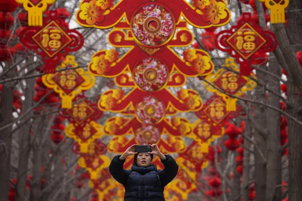 北京地坛公园，居民们在中国农历新年到来之前在挂满红灯笼的树上留影纪念。人们聚集在马尼拉唐人街区一家购物中心展出的500英尺长的龙装置旁。