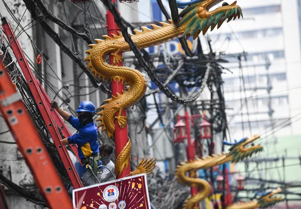 工人们在马尼拉唐人街的龙形路灯旁固定电缆线，与商场里的龙形装饰合影。 - 俄罗斯卫星通讯社