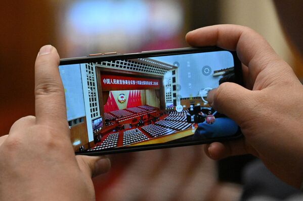 2024年3月4日，在北京人民大会堂举行的中国十四届全国人大二次会议开幕式前，一名记者用手机拍摄会场内部照片。 - 俄罗斯卫星通讯社