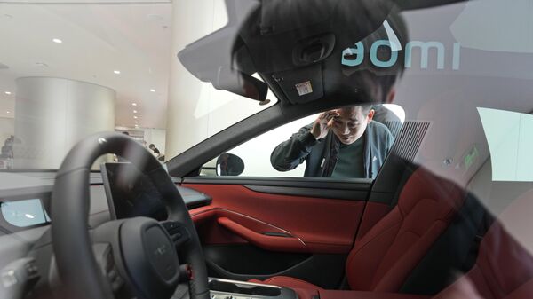 Мужчина заглядывает в салон электромобиля Xiaomi SU7, выставленного на выставке в Пекине  - 俄罗斯卫星通讯社
