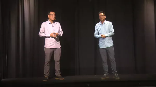 圖片中的兩個人物分別是真實存在的人和虛擬的光學人像。虛擬的光學人像是通過採集真實人物的影像數據，並利用人工智能技術處理後生成的。 - 俄羅斯衛星通訊社