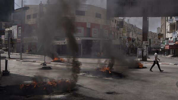 Палестинец проходит мимо горящих шин во время столкновений с израильскими войсками в городе Дженин на Западном Берегу, - 俄罗斯卫星通讯社