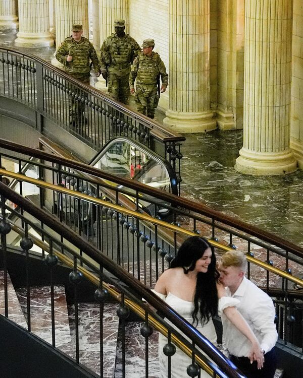 8月16日，哥倫比亞特區國民警衛隊隊員在華盛頓聯合車站內巡邏，一對情侶正在拍攝婚紗照。 - 俄羅斯衛星通訊社