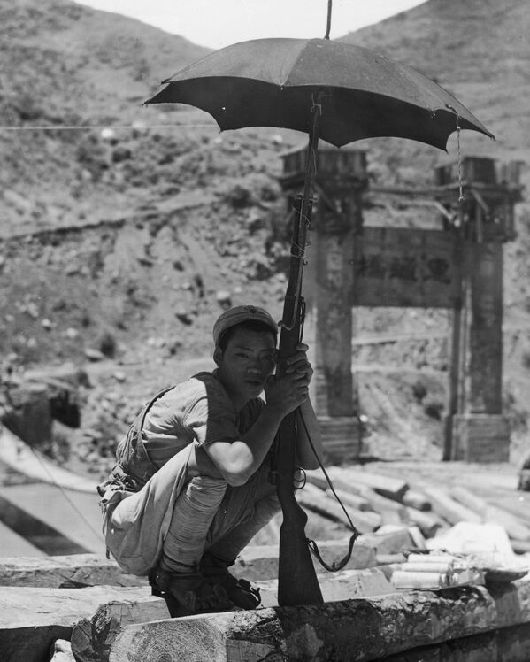 1944年，一名年轻的中国士兵站岗守卫缅甸萨尔温河的惠通桥，他用架在步枪上的阳伞遮阳。在1942年日本军队占领缅甸之后，中国士兵成为盟军解放缅甸努力的一部分。在随后的两年中，激烈的战斗以游击战的形式零星进行，直到英军和中国军队于1945年逐渐重新控制该地区。 - 俄罗斯卫星通讯社