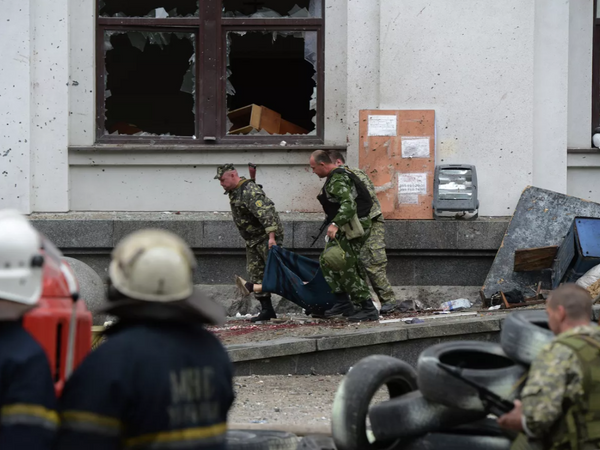 卢甘斯克地区行政大楼遭乌克兰空军空袭，民兵抬着一名遇难者。 - 俄罗斯卫星通讯社