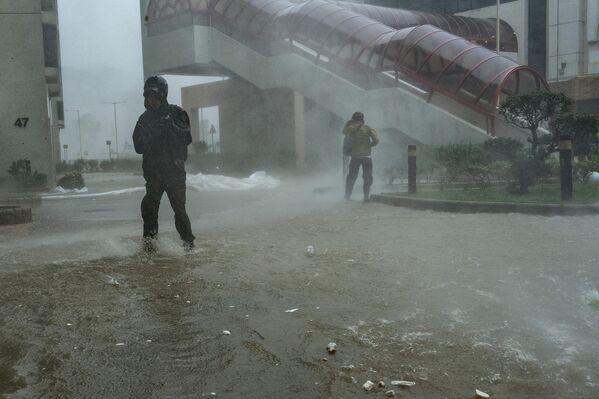 2025年9月24日星期三，超强台风&quot;桦加沙&quot;逼近香港，媒体记者在杏花邨区域的积水中涉水前行。 - 俄罗斯卫星通讯社