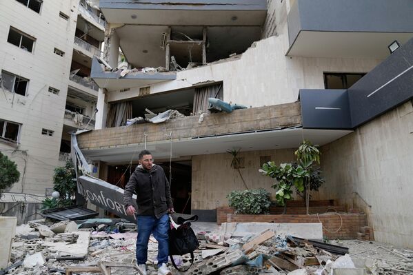 在哈兹米耶，一名男子提着行李离开一家被空袭损毁的酒店。 - 俄罗斯卫星通讯社