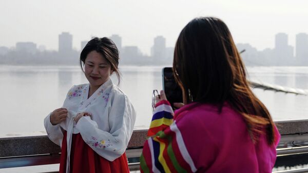 身着传统朝鲜族服装的游客在鸭绿江边拍照 - 俄罗斯卫星通讯社