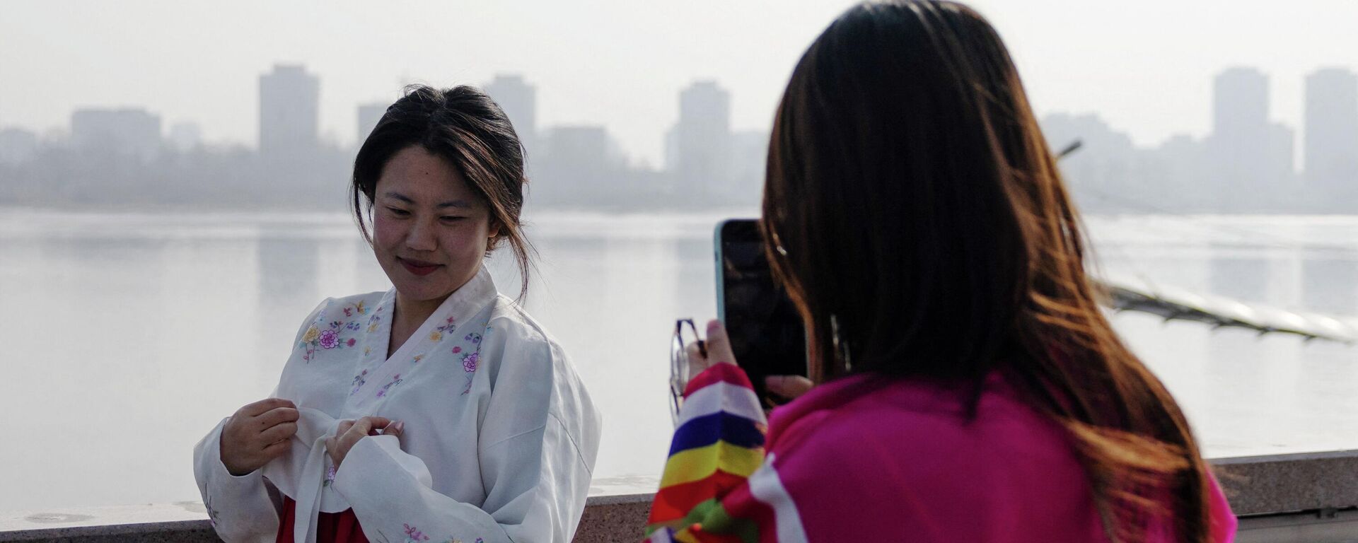 身着传统朝鲜族服装的游客在鸭绿江边拍照 - 俄罗斯卫星通讯社, 1920, 11.03.2026