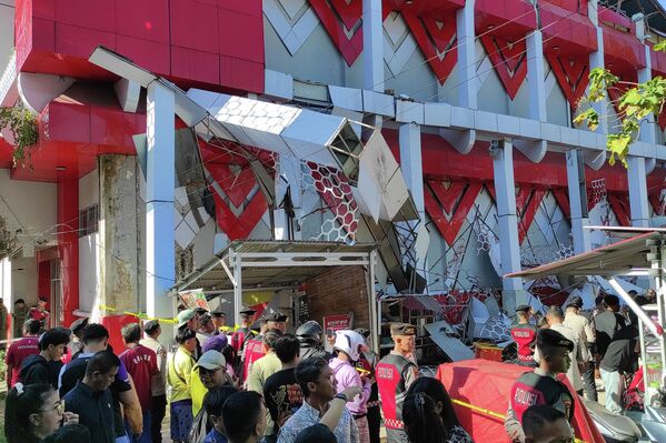 2026年4月2日星期四，印度尼西亚北苏拉威西省万鸦老，警察正在勘查地震后的受损建筑，周围聚集了围观群众。 - 俄罗斯卫星通讯社