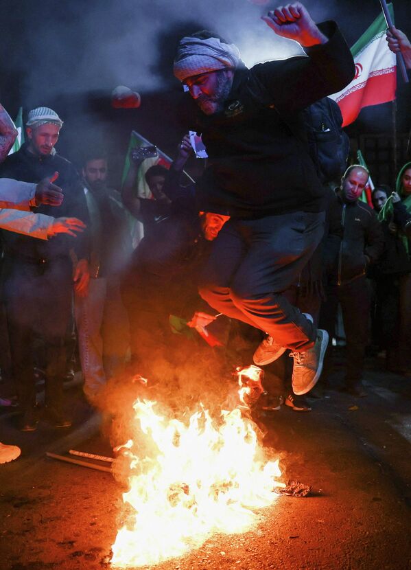 4月8日，美伊宣布停火两周后，伊朗人聚集在一起，一名男子踩踏燃烧的美国和以色列国旗。 - 俄罗斯卫星通讯社