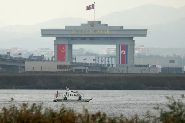 一艘中国检查船沿鸭江航行，经过位于中朝新鸭绿江大桥尽头的一座朝鲜海关建筑 - 俄罗斯卫星通讯社