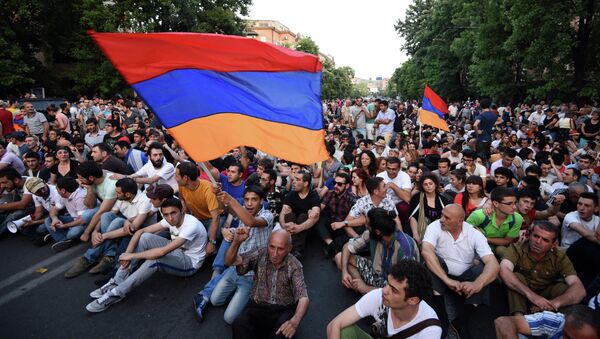 Demonstrators wave their national flags as they sit during a protest against the increase of electricity prices in Yerevan, the capital of Armenia, on June 22, 2015. - 俄罗斯卫星通讯社