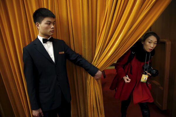 中国全国政协会议在北京开幕，工作人员为来访女宾拉开帘幕。 - 俄罗斯卫星通讯社