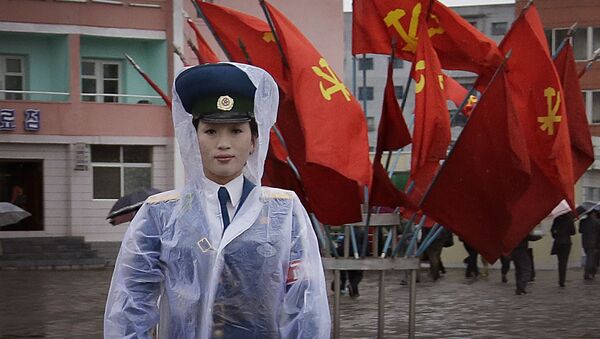 一名朝鲜女交警站在用执政党党旗装点的朝鲜最高建筑物 - 俄罗斯卫星通讯社