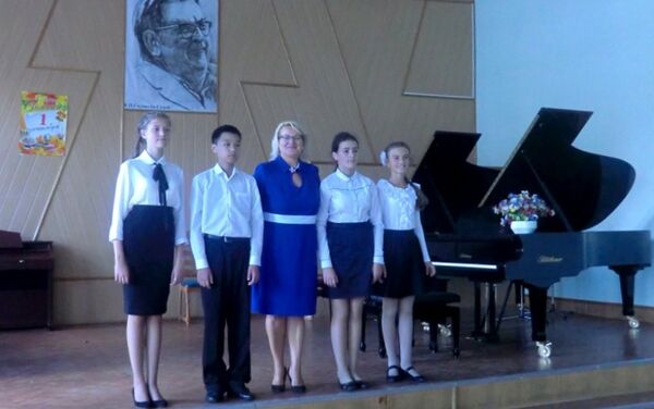 “8手聯彈”四人組合和鋼琴老師奧麗嘉·茹科娃(中)在音樂學校表演廳舞台上 - 俄羅斯衛星通訊社