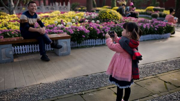 Девочка фотографирует отца в преддверии Дня основания КНР в Пекине - 俄罗斯卫星通讯社