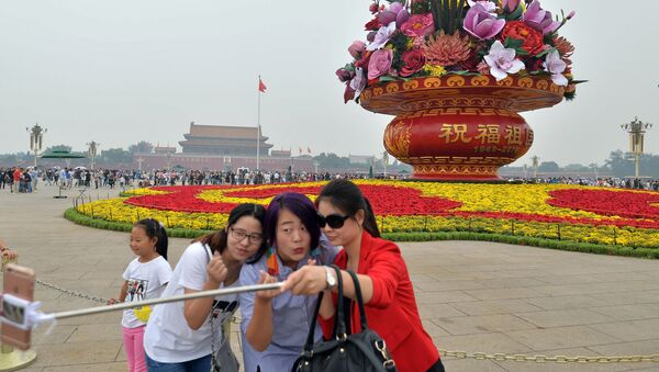 Прохожие делают селфи перед гигантской цветочной корзиной на площади Тяньаньмэнь в Пекине в преддверии Дня образования КНР - 俄罗斯卫星通讯社