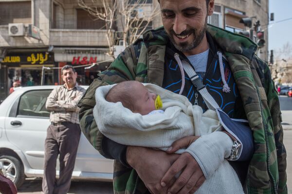 在停戰首日的大馬士革街道上，一名男子帶著一名嬰兒 - 俄羅斯衛星通訊社