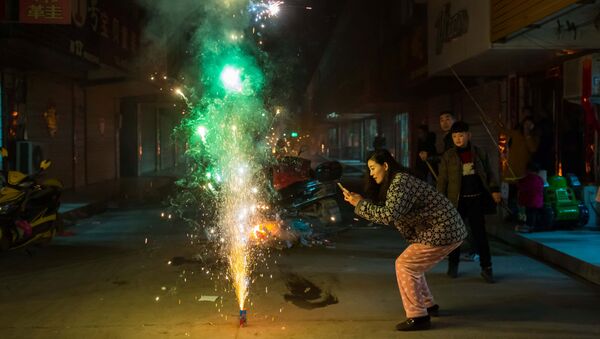 Женщина фотографирует фейерверк в канун китайского Нового года в городе Ляньюньган, провинция Цзянсу, Китай - 俄羅斯衛星通訊社