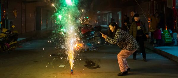 Женщина фотографирует фейерверк в канун китайского Нового года в городе Ляньюньган, провинция Цзянсу, Китай - 俄罗斯卫星通讯社