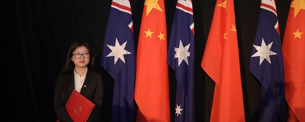 A woman holding a copy of the free trade agreement (FTA) stands next to national flags of China and Australia A woman holding a copy of the free trade agreement (FTA) stands next to national flags of China and Australia - 俄罗斯卫星通讯社