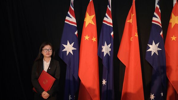A woman holding a copy of the free trade agreement (FTA) stands next to national flags of China and Australia - 俄罗斯卫星通讯社