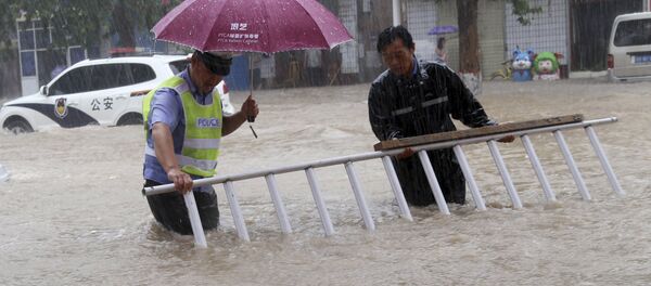 A man helps a traffic policeman move away a barrier on a flooded road in Wanrong County, north China's Shanxi Province - 俄羅斯衛星通訊社
