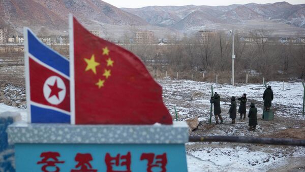 Concrete marker depicting the North Korean and Chinese national flags with the words China North Korea Border - 俄罗斯卫星通讯社