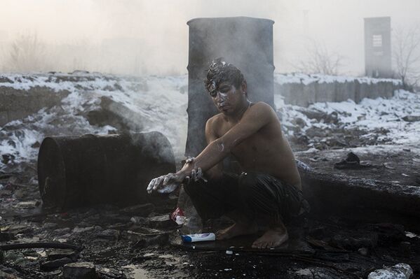 难民在贝尔格莱德的。 亚历山德罗·马丁内斯·韦列斯，西班牙。 图为：一名青年在为住在贝尔格莱德火车站废弃仓库附近的阿富汗和巴基斯坦难民烧水的一个大桶里洗澡。 - 俄罗斯卫星通讯社