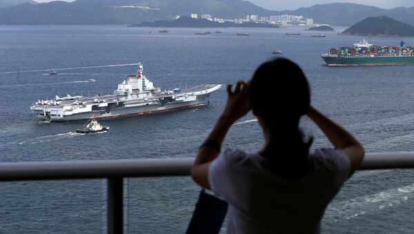 An onlooker takes a photo as China's aircraft carrier Liaoning sails into Hong Kong - 俄羅斯衛星通訊社