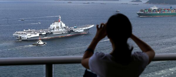 An onlooker takes a photo as China's aircraft carrier Liaoning sails into Hong Kong - 俄罗斯卫星通讯社