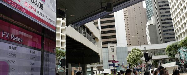 People stand next to an electronic board showing the Hong Kong Stock Exchange index - 俄罗斯卫星通讯社