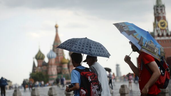 Туристы под зонтом во время дождя на Красной площади в Москве - 俄罗斯卫星通讯社