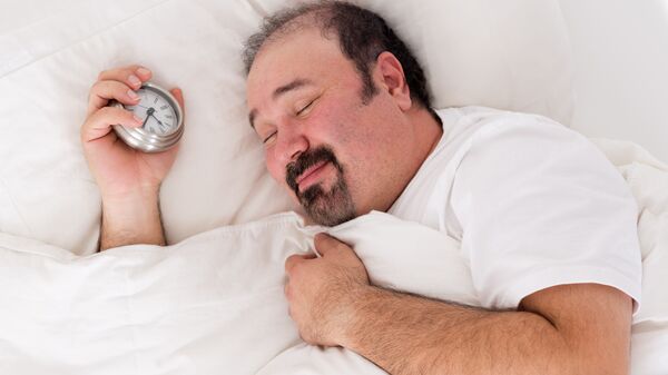 Спящий мужчина с будильником в руке - 俄罗斯卫星通讯社