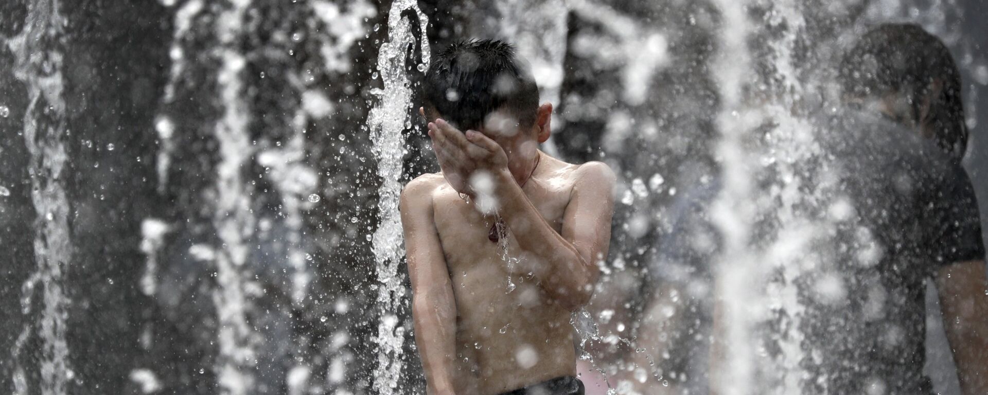 A boy reacts after being splashed by water in a fountain at a shopping mall in Beijing, where a heat wave brought temperatures above 95 degrees (35 C) - 俄罗斯卫星通讯社, 1920, 10.07.2023