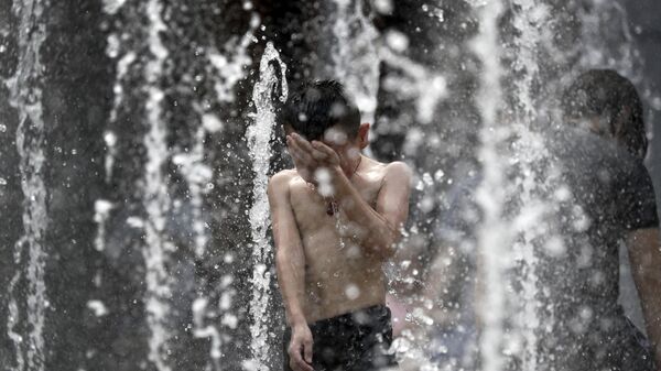 A boy reacts after being splashed by water in a fountain at a shopping mall in Beijing, where a heat wave brought temperatures above 95 degrees (35 C) - 俄罗斯卫星通讯社