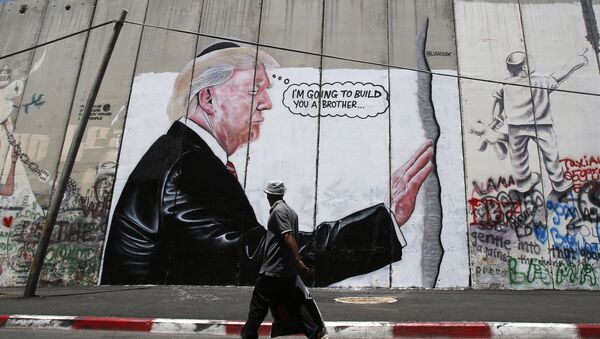 A Palestinian man walks past graffiti depicting US President Donald Trump on the controversial Israeli separation barrier - 俄羅斯衛星通訊社