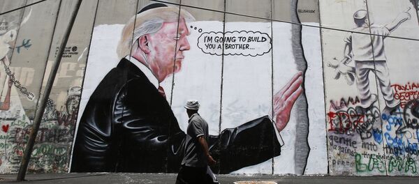 A Palestinian man walks past graffiti depicting US President Donald Trump on the controversial Israeli separation barrier A Palestinian man walks past graffiti depicting US President Donald Trump on the controversial Israeli separation barrier - 俄罗斯卫星通讯社